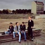 Die Band Depeche Mode 1985 sitzt auf einem Bretterstapel in Berlin