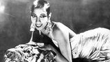 Josephine Baker liegt auf einem Tigerfell und trägt große Ohrringe