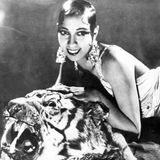Josephine Baker liegt auf einem Tigerfell und trägt große Ohrringe