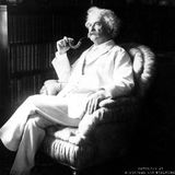 Mark Twain mit Pfeife und weißem Anzug in einem Sessel.