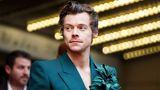 Harry Styles mit petrolblauem Sakko und Blume am Revers