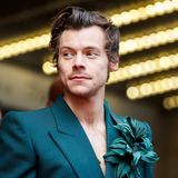 Harry Styles mit petrolblauem Sakko und Blume am Revers