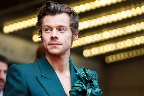 Harry Styles mit petrolblauem Sakko und Blume am Revers