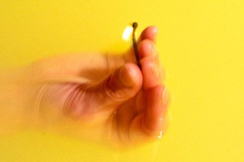 Hand im Wasser mit brennendem Streichholz zwischen den Fingern