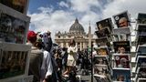 Nicht nur die Kardinäle sind gespannt, wer aus dem Konklave als nächster Papst hervorgeht. Eine TV-Reporterin macht ihren Aufsager zwischen Petersdom und Souvenirstand