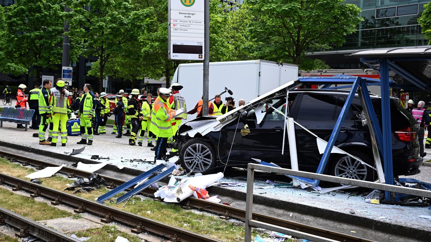 Einsatzkräfte der Polizei und Feuerwehr stehen in München an der Unfallstelle