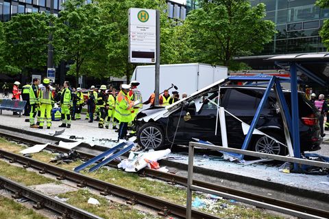 Einsatzkräfte der Polizei und Feuerwehr stehen in München an der Unfallstelle