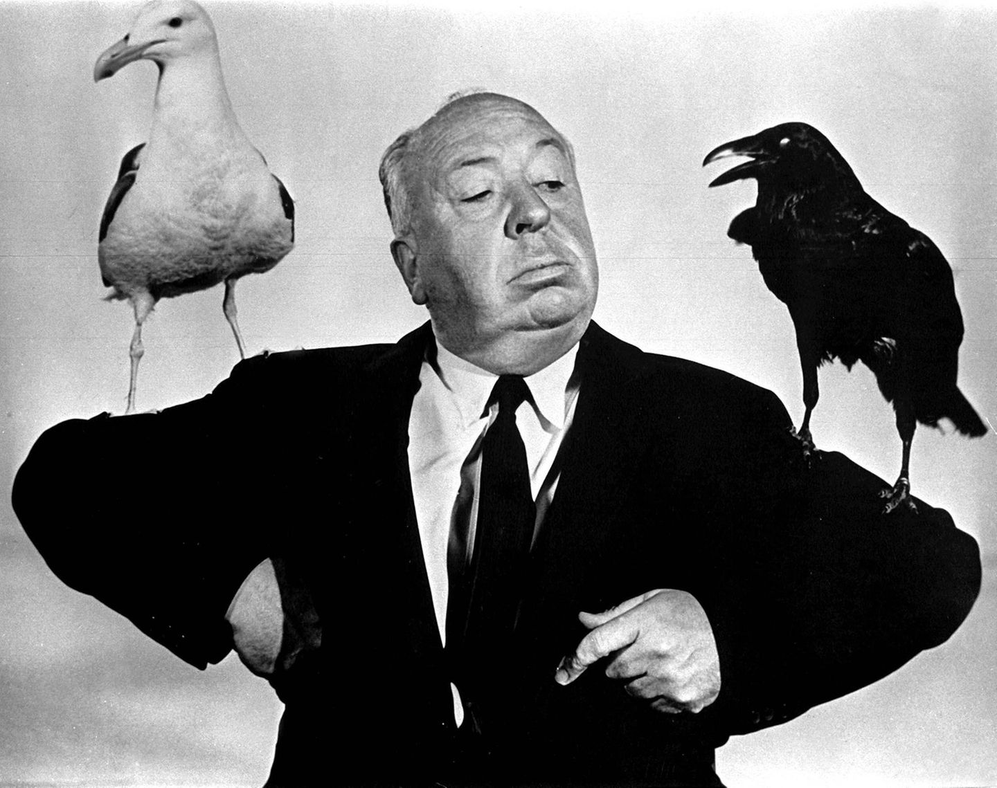 Alfred Hitchcock mit je einer Möwe und einer Krähe auf den Schultern