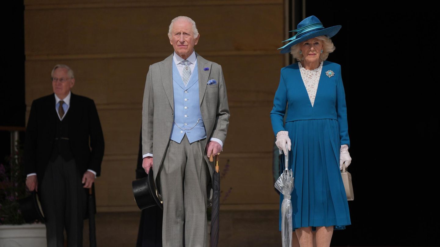 Gastgeber König Charles im grauen Frack und Camilla im blauen Kostüm treten aus dem Buckingham Palast in den Garten