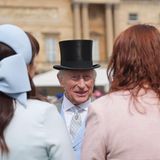 König Charles mit schwarzem Zylinder im Gespräch mit zwei Frauen aus dem Volk