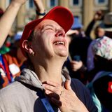 Frau fasst sich lächelnd und in Richtung Himmel strahlend an die Brust