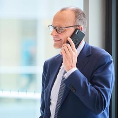 Friedrich Merz läuft mit dem Handy am Ohr durch die Flure des Bundestags in Berlin