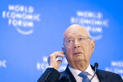 WEF-Gründer Klaus Schwab sitzt im Anzug vor einer blauen Wand mit dem Weltwirtschaftsforum-Logo