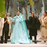 Der Fendi-Designer Kim Jones holt Linda Evangelista zurück in die Mode – als Gesicht für eine Jubiläumskampagne: Die Fendi-"Baguette Bag" wird 25 Jahre alt. Bei ihrem ersten Laufstegauftritt nach langer Zeit trägt Evangelista einen türkisfarbenen Mantel. Sie wird von Silvia Venturini-Fendi (l.), den Designern Marc Jacobs und Kim Jones (r.) und dem Publikum gefeiert