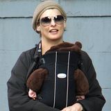 Linda Evangelista mit Sonnenbrille in New York, sie trägt ihr Baby in einer Trage vor der Brust