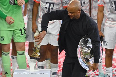 Vincent Kompany, Trainer des FC Bayern, hält in einer Hand die Meisterschale und in der anderen einen Deko-Kakadu