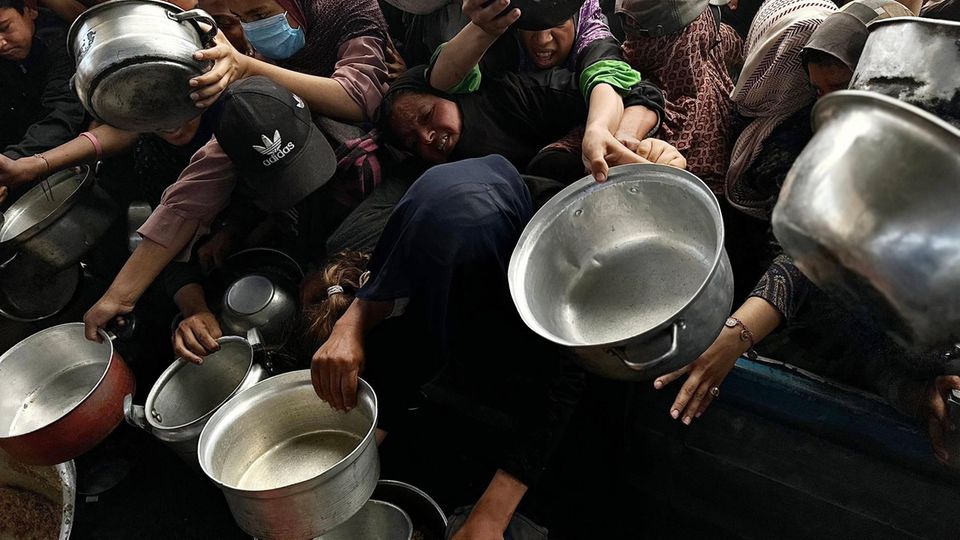 Kinder und Erwachsene in Gaza ringen mit ihren Töpfen bei der Essensausgabe um eine Essensausgabe