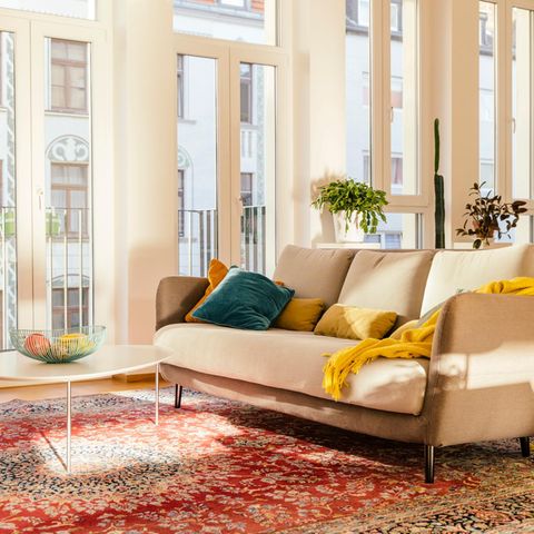 Immobilienkauf Symbolbild: Großzügiges modernes Wohnzimmer in warmen Farben mit Orientteppich