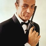 Sean Connery als James Bond im Portrait. Sein Blick ist lässig, mit der Hand hält er eine Waffe an sein Gesicht