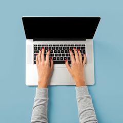 Frau sitzt vor aufgeklapptem Laptop