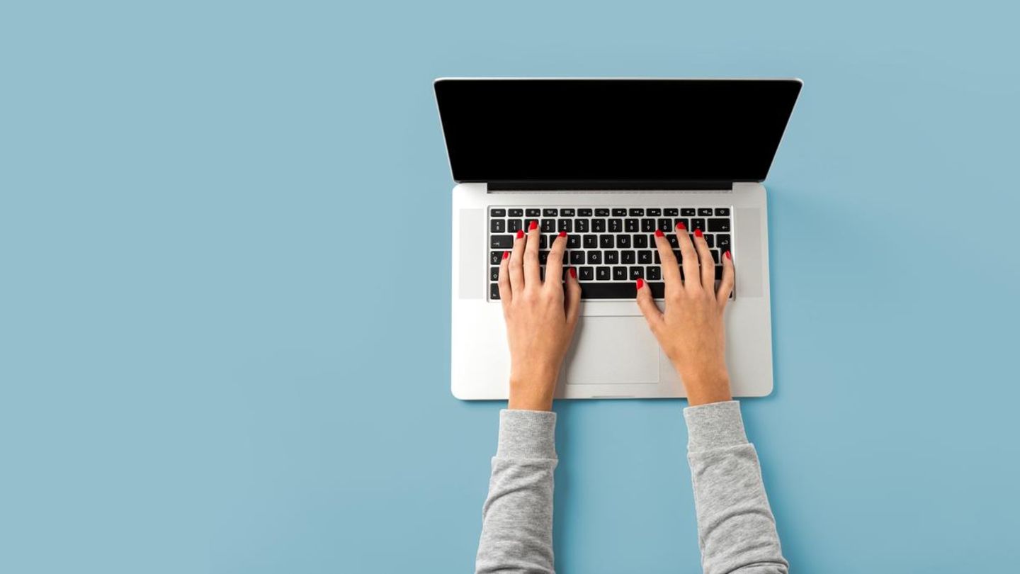 Frau sitzt vor aufgeklapptem Laptop
