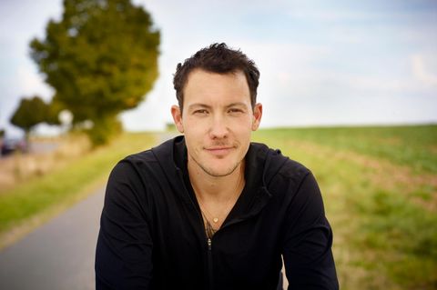 Brix Schaumburg, ein Mann im schwarzen Pulli steht vor einer Landstrasse