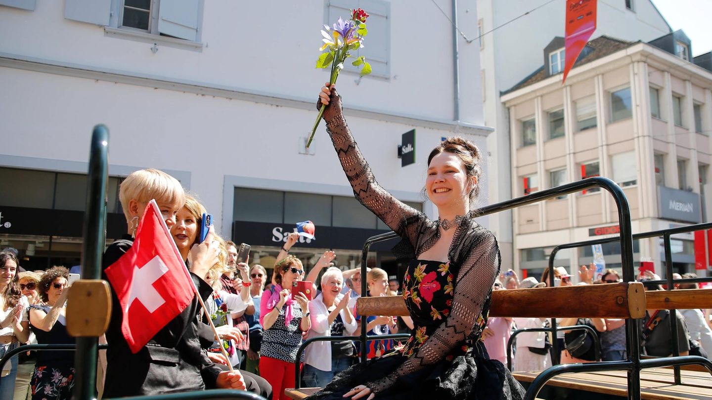 Zoë Më auf einem Wagen in Tracht und mit Blumen in der Hand