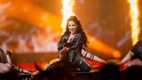 Justyna Steczkowska kniet auf der Bühne, hinter ihr brennen Feuersäulen für die Show