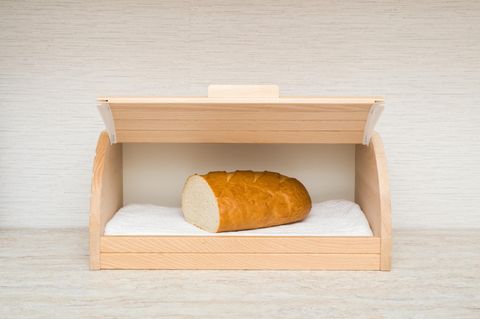 Die Hälfte eines frischen Weißbrots im geöffneten Holzbrotkasten