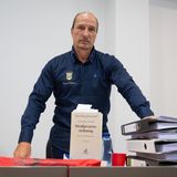 Peter Fitzek steht in einem Gerichtssaal, vor ihm eine Strafprozessordnung