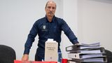 Peter Fitzek steht in einem Gerichtssaal, vor ihm eine Strafprozessordnung