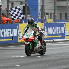 Ein Rennfahrer fährt mit seinem Motorrad über die Ziellinie