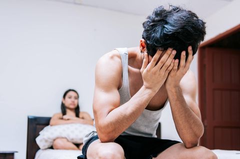 Erektionsproblem: junger Mann sitzt mit verzweifeltem Gesicht im Bett
