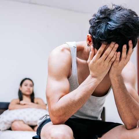 Erektionsproblem: junger Mann sitzt mit verzweifeltem Gesicht im Bett
