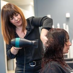 Friseurin stylt Haare ihrer Kundin