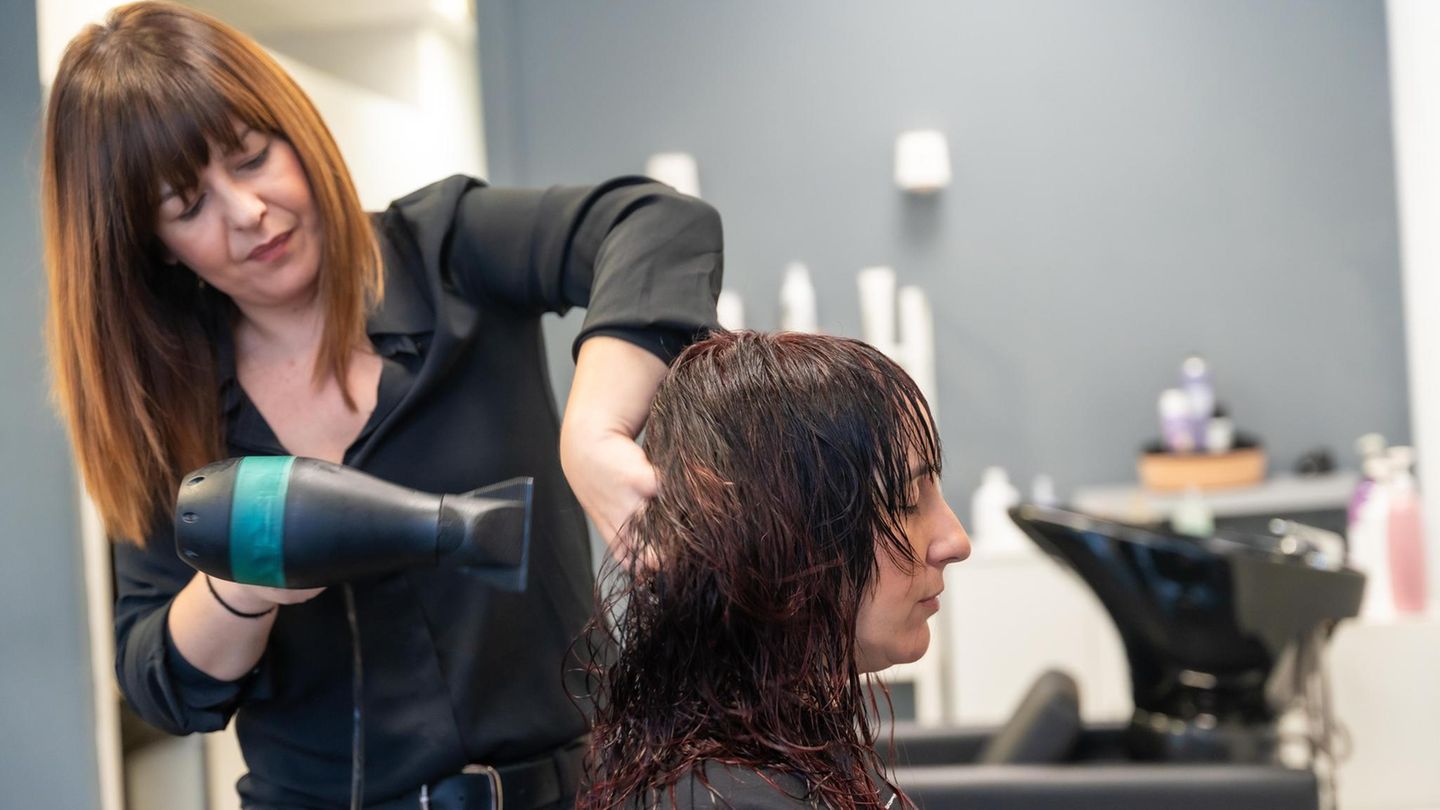 Friseurin stylt Haare ihrer Kundin Friseurin stylt Haare ihrer Kundin