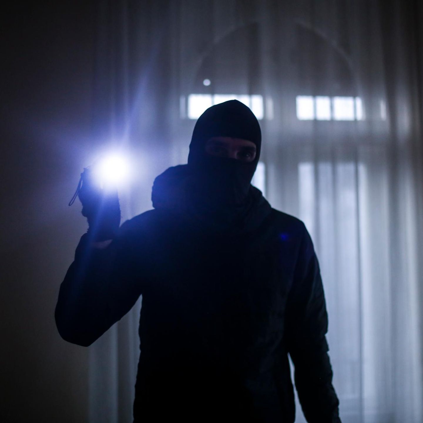 Maskierter Mann mit Taschenlampe