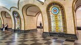 Bahnsteighalle mit Pfeilern und bunten Glasmalereien