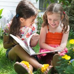 Kinder-Wettbewerb: Eine große Schester liest der kleineren ein Buch vor