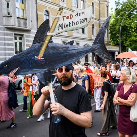 A man holds up a self -painted rental shark: demonstration for cheap apartment rents in Berlin