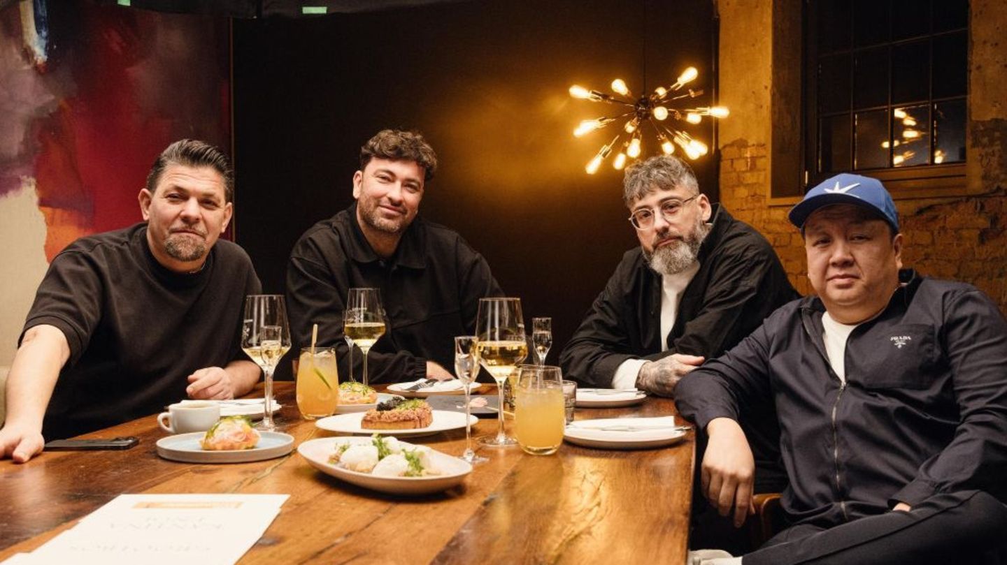 Am Kitchen Impossible Tisch sitzen vier Männer, zwei Köche und zwei Rapper