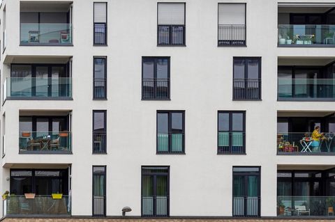 Frau hängt Wäsche auf ihrem Balkon in einem modernen Mehrfamilienhaus auf