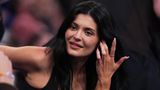 Kylie Jenner sitzt im schwarzen Top in der ersten Reihe und schaut aufs Feld