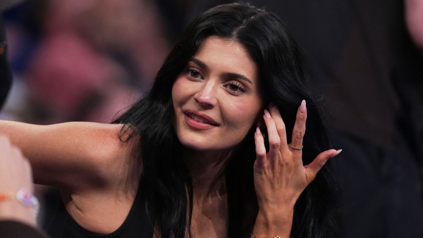 Kylie Jenner sitzt im schwarzen Top in der ersten Reihe und schaut aufs Feld