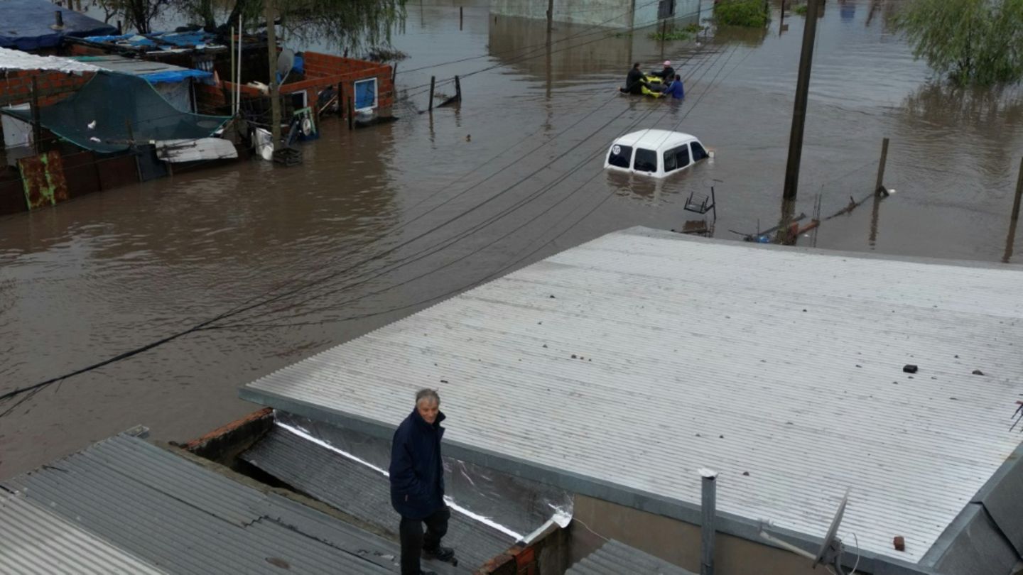 Ein Mann auf dem Dach seines überfluteten Hauses