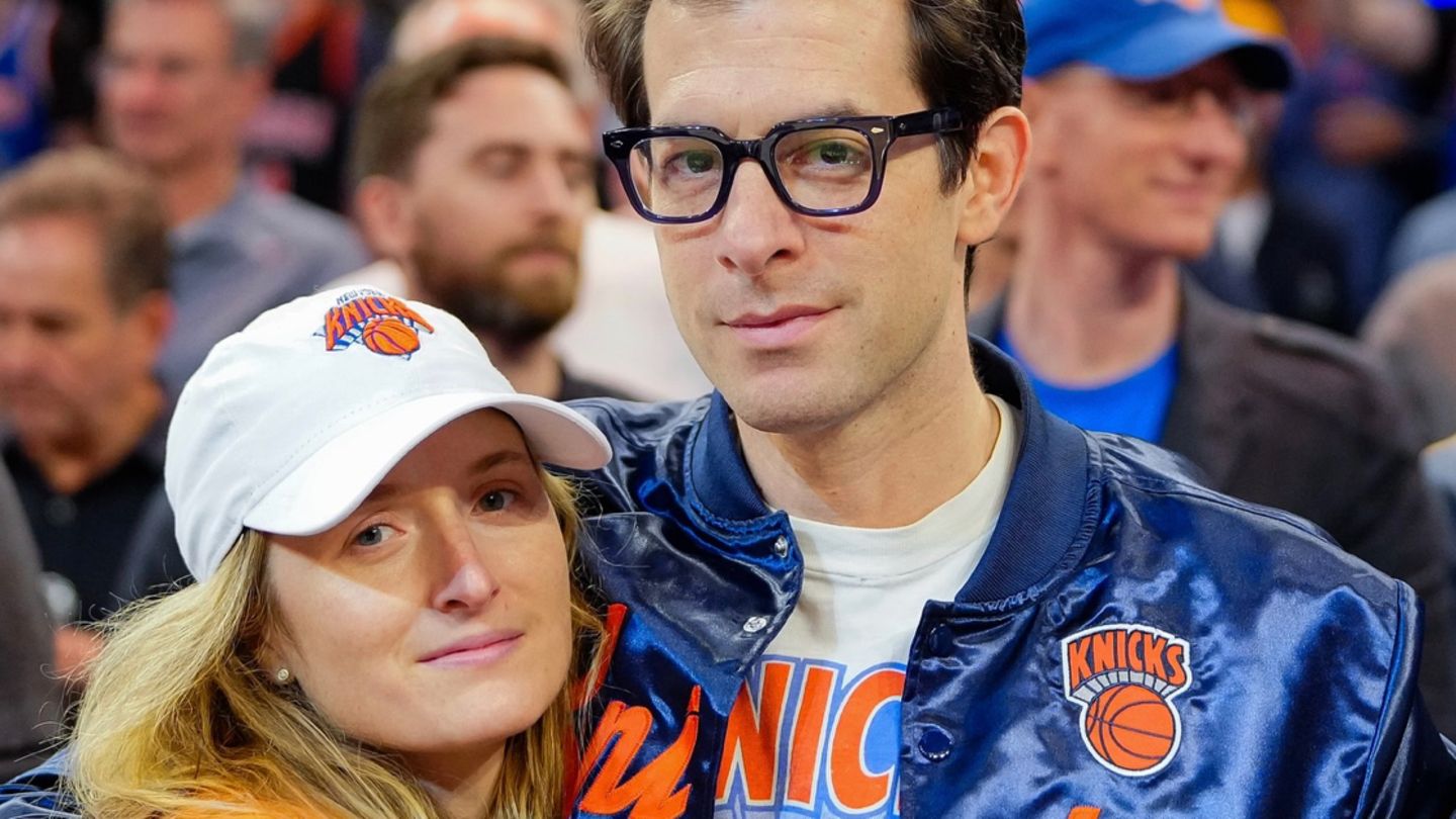 Mark Ronson in Knicks-blauer Jacke mit Ehefrau Mamie Gummer im Arm, die Knicks-Orange trägt