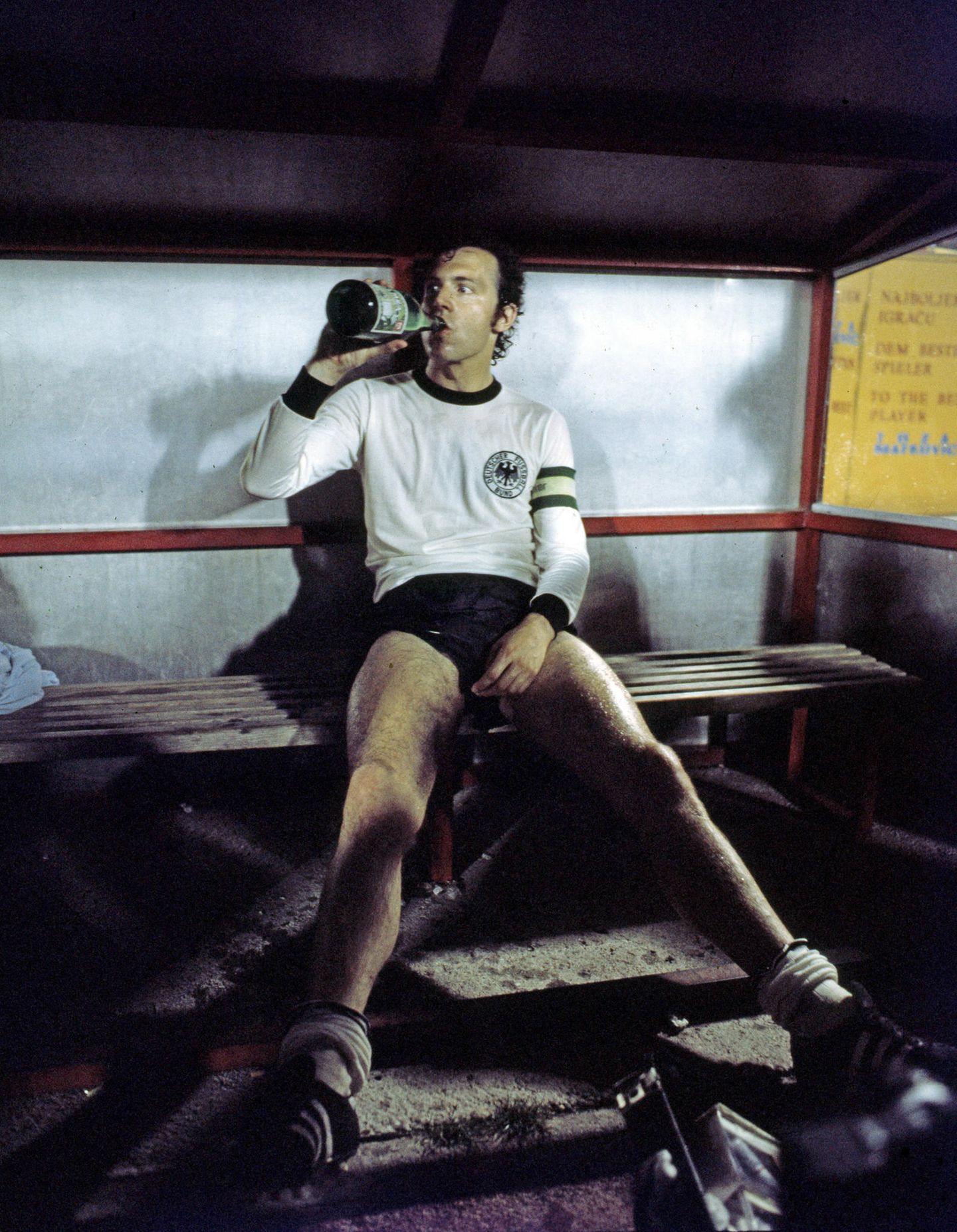Franz Beckenbauer: Der Regisseur Franz Beckenbauer sitzt ausgelaugt auf einer Bank und trinkt aus einer Flasche
