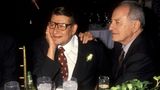 Yves Saint Laurent und sein Freund Pierre Bergé sitzen an einem Tisch. Er stützt seinen Kopf auf die Hand