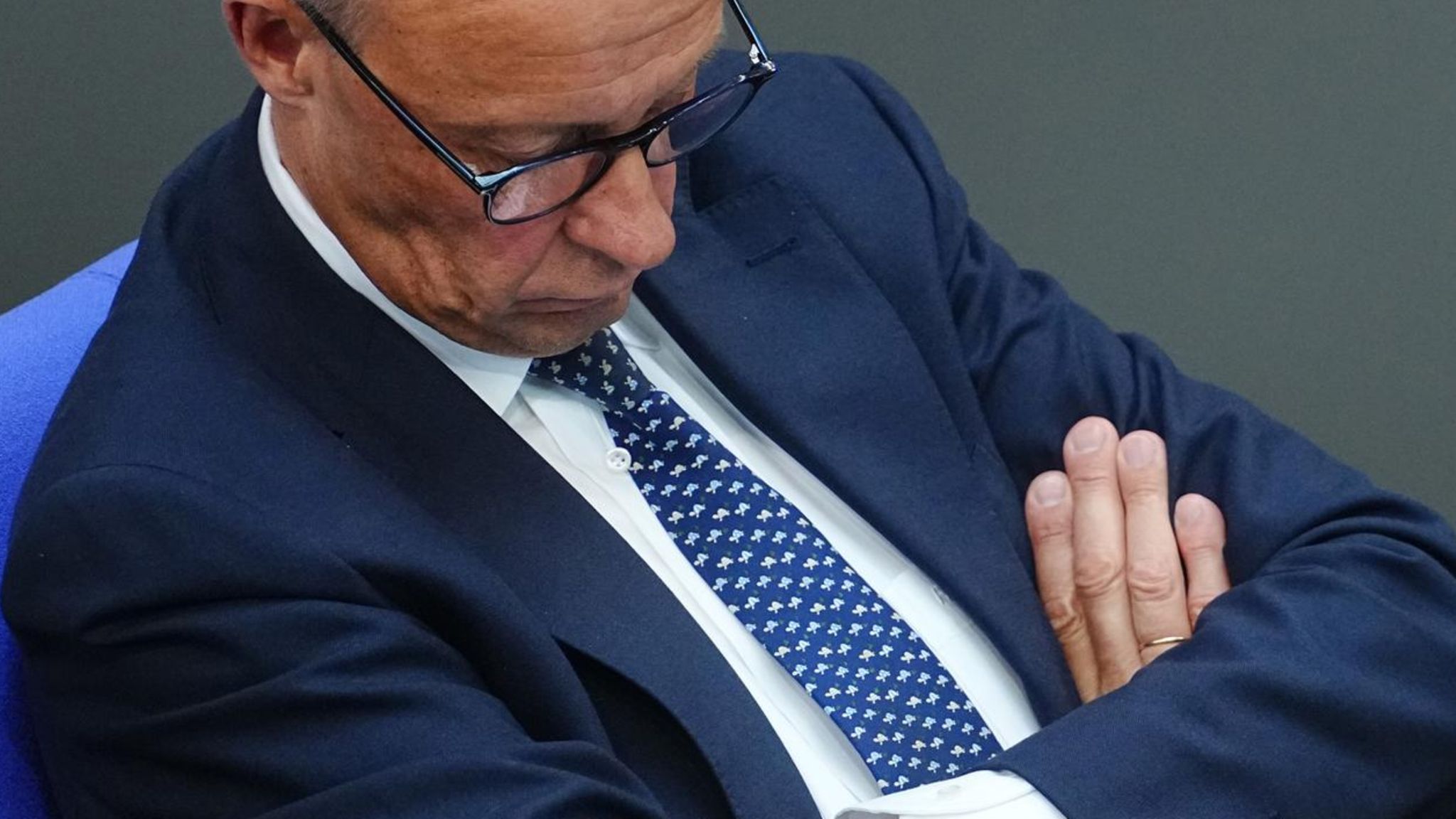 Friedrich Merz sitzend im blauen Anzug, er scheint zu schlafen