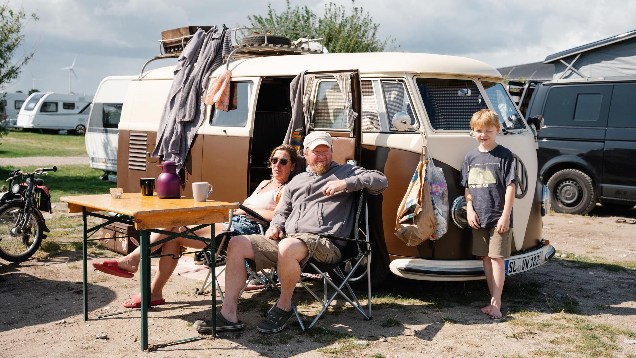 Eine Familie sitzt vor ihrem VW Bulli im Ahoi Camp Fehmarn